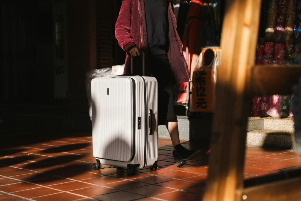 A person is walking with a white suitcase.