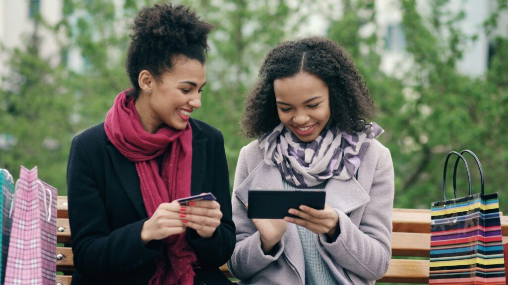 Happy ladies chatting while looking at tablet and a card.